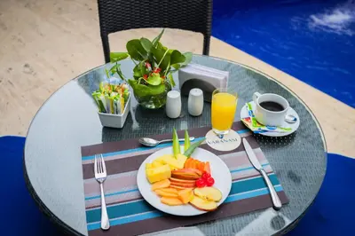 a table with a plate of fruit and a cup of orange juice at Varanasi Hotel Boutique Aeropuerto in Cartagena de Indias