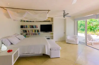 a bedroom with a large bed and a tv at Villa Los Cocos Baru in Baru