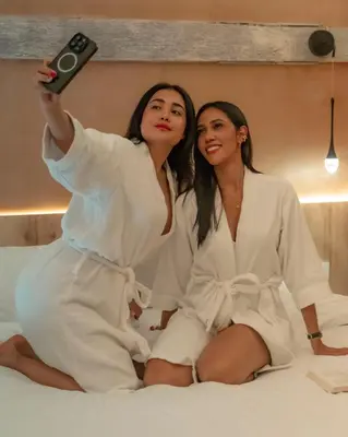 two women sitting on a bed holding a remote control at Hotel Villa Alta Guest House in Cartagena de Indias