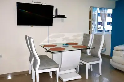 a dining room table with chairs and a television on a wall at Apartamento vacacional El Laguito Cartagena in Cartagena de Indias