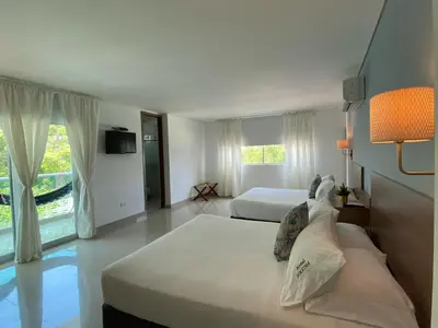 a bedroom with two beds and a large window at Hotel Soleira in Tolú