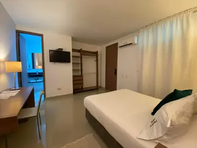 a bedroom with a bed and a desk and a television at Hotel Soleira in Tolú