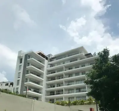 a large white building with a tree in front of it at Apartamento Bello Horizonte Santamarta in Santa Marta