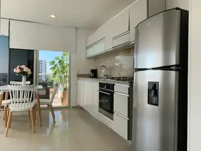 a kitchen with a stainless steel refrigerator and a table at Apartamento Bello Horizonte Santamarta in Santa Marta