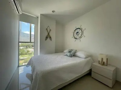 a white bedroom with a bed and a window at Apartamento Bello Horizonte Santamarta in Santa Marta
