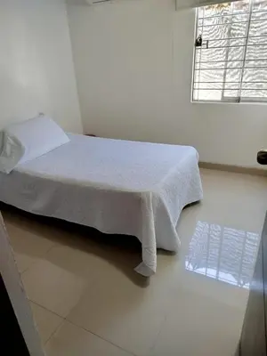 a bedroom with a white bed and a window at Habitación Colibrí in Barranquilla