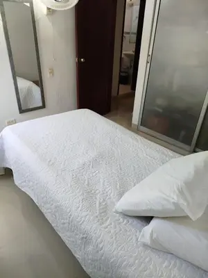 a bed with white sheets and pillows in a room at Habitación Colibrí in Barranquilla
