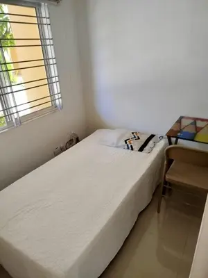 a small bedroom with a bed and a chair at Habitación Colibrí in Barranquilla