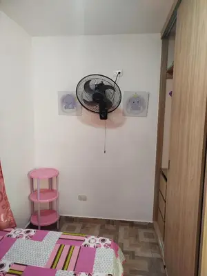 a bedroom with a fan on the wall and a pink stool at La casita de jo in Cartagena de Indias