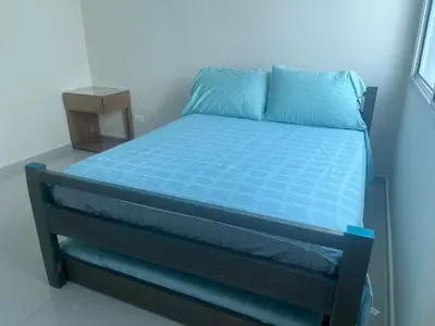 a bedroom with a bed with blue sheets and a night stand at Lux Oceanfront Apartment in Cartagena de Indias