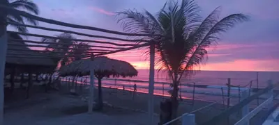 a view of a beach with palm trees and a sunset at Cabaña Flor de Loto in San Bernardo del Viento