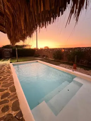 a swimming pool with a sunset in the background at Surf Mojarra Beach Habitación privada con vista al mar in Salina de Rey