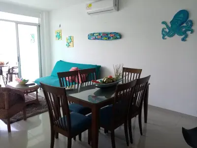 a dining room with a table and chairs and a couch at Apartamento Frente al Mar in Santa Marta