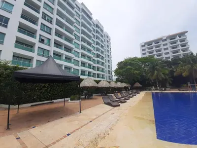 a pool with chairs and umbrellas next to a building at Apartamento Frente al Mar in Santa Marta