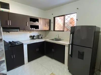 a kitchen with brown cabinets and a black refrigerator at Cabaña Tolu Sucre in Santiago