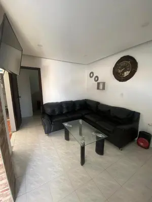 a living room with a black couch and a glass table at Cabaña Tolu Sucre in Santiago