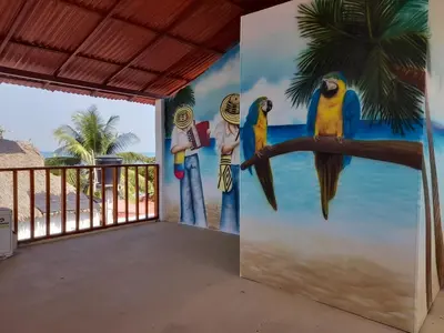 a mural of parrots on a wall in a room at Cabaña frente al mar de San Antero in San Antero