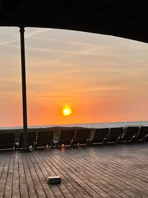 a row of benches on a pier with the sunset at Love en Mojarra Beach Habitación privada vista al mar in Salina de Rey