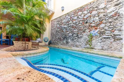 a swimming pool in front of a building with a stone wall at Casa azul in Cartagena de Indias