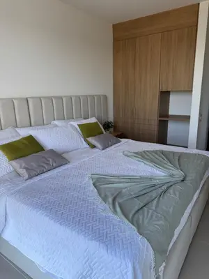 a bedroom with a large white bed with green pillows at Baia Kristal 5I in Estación El Salto