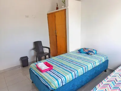 a bedroom with a bed and a chair and a cabinet at Apartamento cerca a la playa in El Porvenir