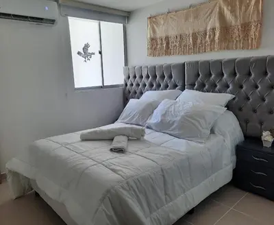 a bedroom with a large bed with a headboard and a window at Apartamento completo in Cartagena de Indias