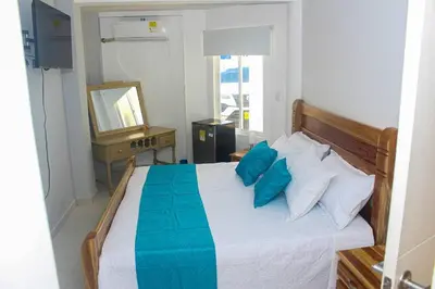 a bedroom with a bed with blue pillows and a mirror at Chalet Ledymar in Cartagena de Indias