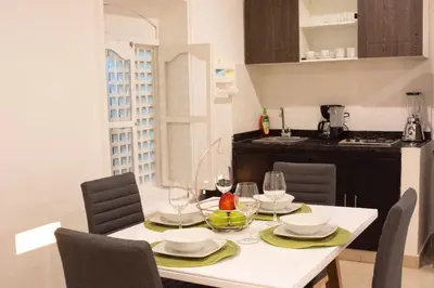 a dining room table with chairs and a white table with wine glasses at Hermoso apto estudio en la ciudad amurallada! in Cartagena de Indias