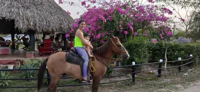 a woman riding a horse with a child on it at Alquiler de caballos y cabalgatas por el Atlántico in Baranoa