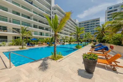 a swimming pool with palm trees and a building at Morros Epic 2 Bedrooms Beachfront by Inmobiliaria MFR in Cartagena de Indias
