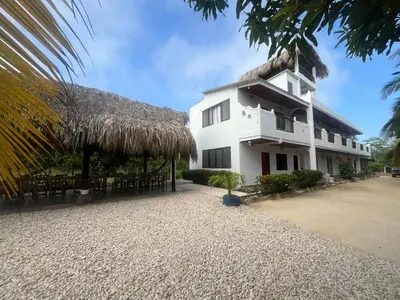 a building with a thatched roof and tables and chairs at Hotel Heliopolis in Coveñas
