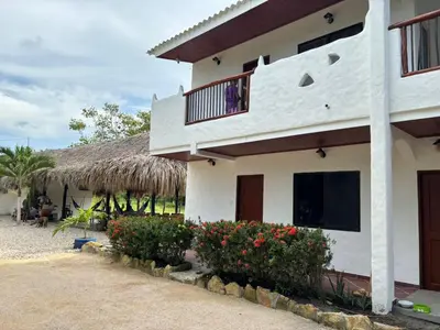 a house with a thatched roof and flowers at Hotel Heliopolis in Coveñas