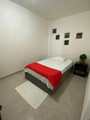a white bedroom with a bed with a red blanket at Casa alojamiento entero - cerca al castillo san Felipe in Cartagena de Indias
