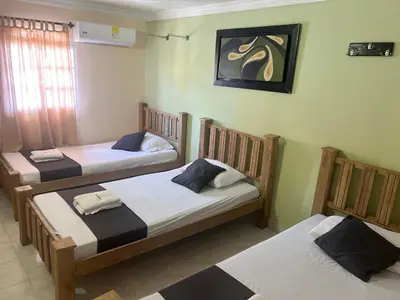 three twin beds in a room with a painting on the wall at Hotel Georgina in Barranquilla