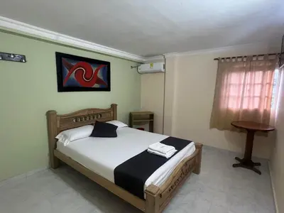 a bedroom with a bed and a table and a window at Hotel Georgina in Barranquilla