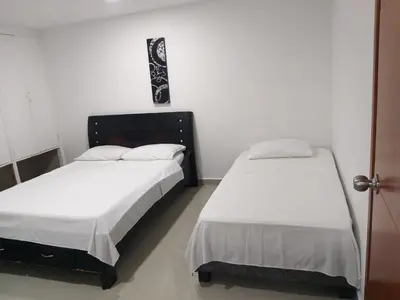 two beds in a room with white walls at Apartamento Moderno con Vista - Piso 12 in Cartagena de Indias