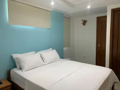 a bedroom with a white bed with a blue wall at Hotel Boulevard 58 in Galapa