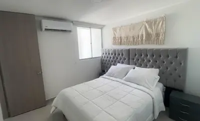 a bedroom with a bed with white sheets and a window at Apartamento cerca al aeropuerto in Cartagena de Indias