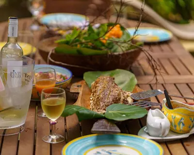 a wooden table with plates of food and a bottle of wine at Hotel Fuerte Mayal in Isla Fuerte