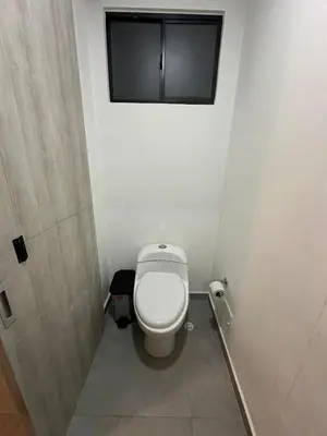 a bathroom with a toilet with a window on the wall at Apartamento Arrecife Golf in Barranquilla