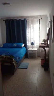 a bedroom with a blue bed and a window at Apartaestudio Ciudad Jardin in Barranquilla