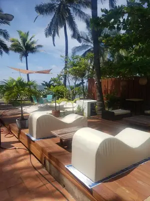 a row of white couches on a deck with palm trees at Vista al Mar in Cartagena de Indias