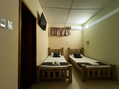 two twin beds in a room with a tv at Hotel Don Fermin in Barranquilla