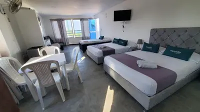 a hotel room with two beds and a table and chairs at Apartahotel hm caribe in Santa Marta