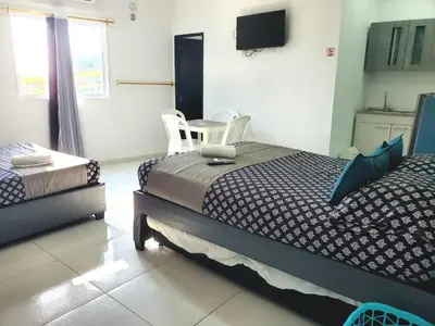 a bedroom with two beds and a flat screen tv at Apartahotel hm caribe in Santa Marta