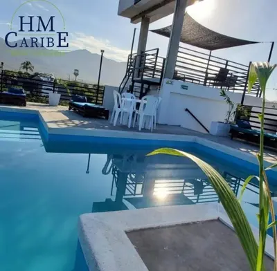 a pool with two white chairs next to a house at Apartahotel hm caribe in Santa Marta