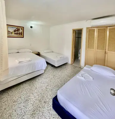 two beds in a hotel room with white sheets at Hotel Casa Fátima in Cartagena de Indias