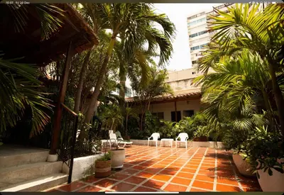 a courtyard with chairs and palm trees and a building at Hotel Casa Fátima in Cartagena de Indias