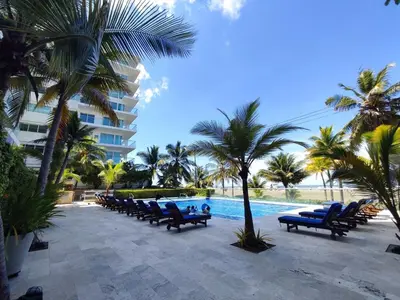 a pool with blue chairs and palm trees and a building at Hermoso Apto playa de Morros! in Cartagena de Indias
