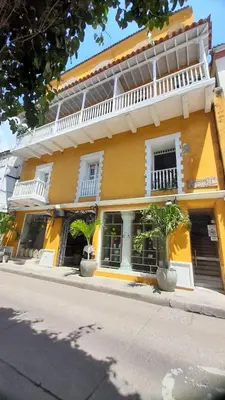 a yellow building with palm trees in front of it at Apartment in Old City Cartagena 3D in Cartagena de Indias